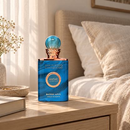 Anfar London Bateig Azul perfume bottle on a pale wooden bedside table beside linen bedding in morning light