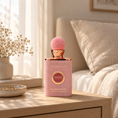 Anfar London Cameo Rosie perfume bottle on a pale wooden bedside table beside linen bedding in morning light