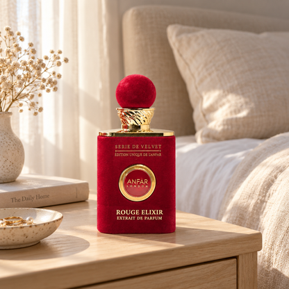 Anfar London Rouge Elixir perfume bottle on a pale wooden bedside table beside linen bedding in morning light