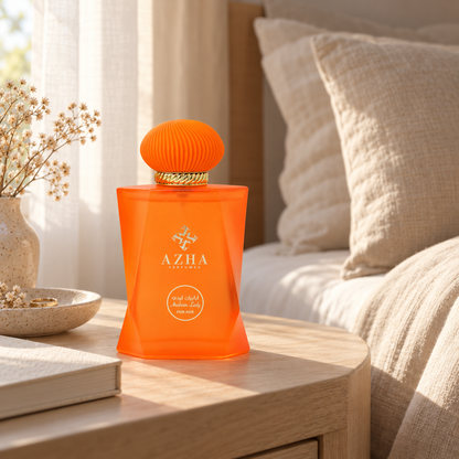 Azha Arabian Lady perfume bottle on a pale wooden bedside table beside linen bedding in morning light