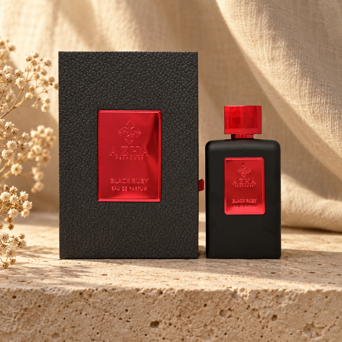 Azha Black Ruby Eau de Parfum 100 ml bottle and charcoal pebbled-leather box with red mirror plaque on a travertine ledge with linen backdrop