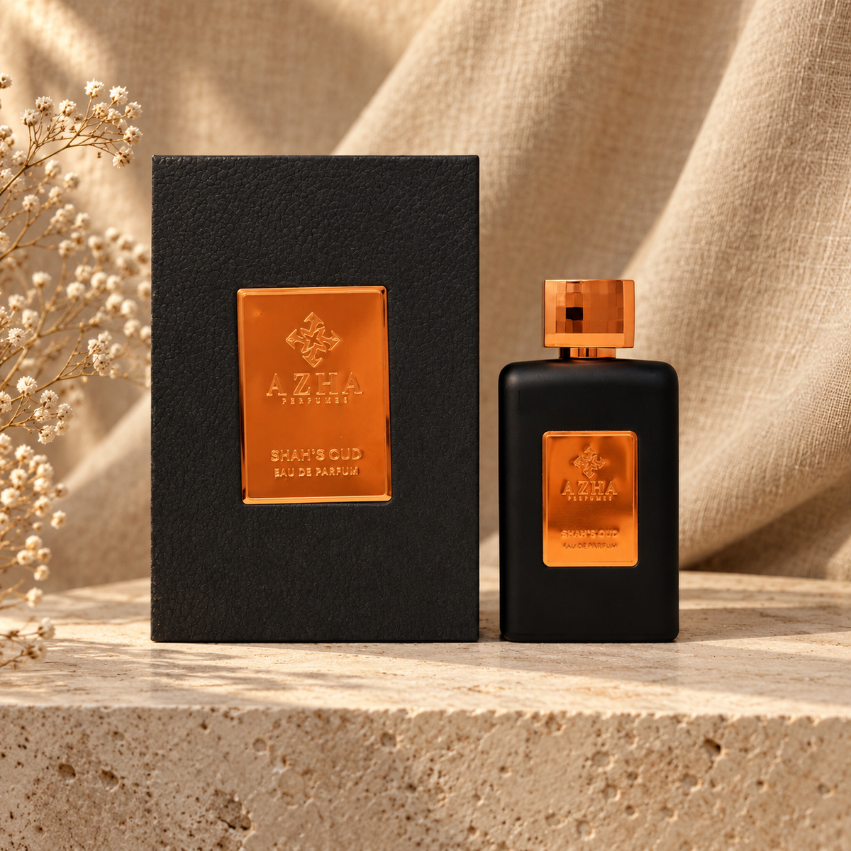 Azha Shah's Oud Eau de Parfum 100 ml bottle and charcoal pebbled-leather box with copper mirror plaque on a travertine ledge with linen backdrop